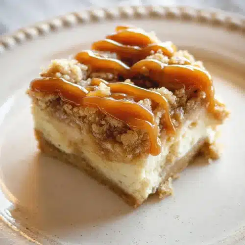 Apple Cheesecake Bars (Perfect for Thanksgiving) 10 Caramel-drizzled apple cheesecake bar with streusel topping on plate