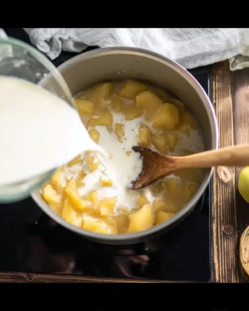 Pouring milk into pot of potatoes and broth for cheese soup