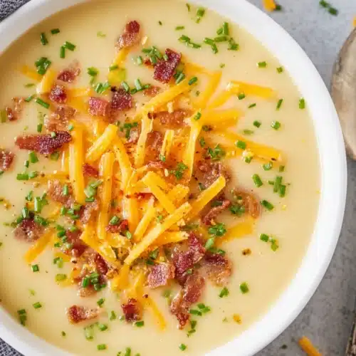 Creamy cheddar cheese potato soup topped with bacon, cheddar, and chives