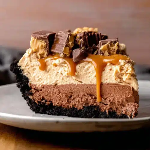 Chocolate Peanut Butter Pie (Thanksgiving Favorite) 11 Slice of chocolate peanut butter pie with Oreo crust, creamy layers, and peanut butter cup topping