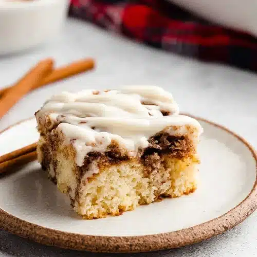 Cinnamon Roll Cake with Cream Cheese Frosting | Perfect Thanksgiving Dessert 7 Moist cinnamon roll cake slice with cream cheese frosting on white plate
