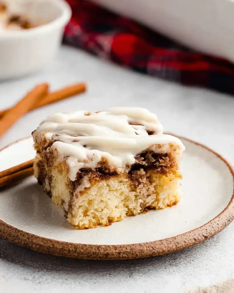 Cinnamon Roll Cake with Cream Cheese Frosting | Perfect Thanksgiving Dessert 1 Moist cinnamon roll cake slice with cream cheese frosting on white plate