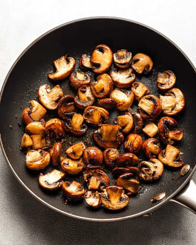 Classic Beef Bourguignon (Christmas Recipe) 6 Golden-brown mushrooms searing in skillet for classic beef bourguignon