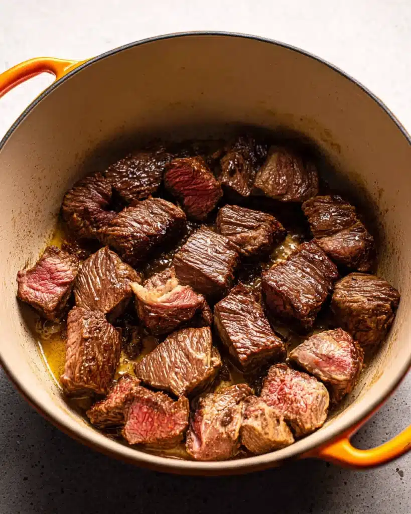 Classic Beef Bourguignon (Christmas Recipe) 3 Beef chuck cubes searing in Dutch oven for classic beef bourguignon