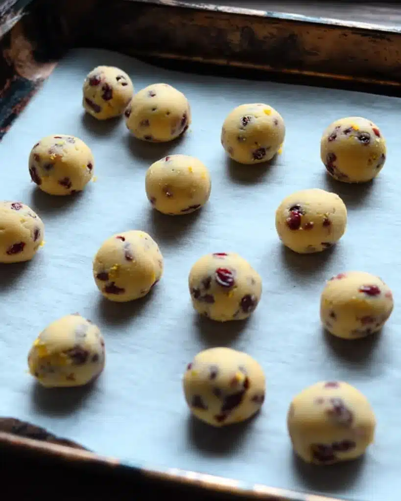 Cranberry Orange Snowball Cookies 8 Rolled cranberry orange cookie dough balls on baking tray