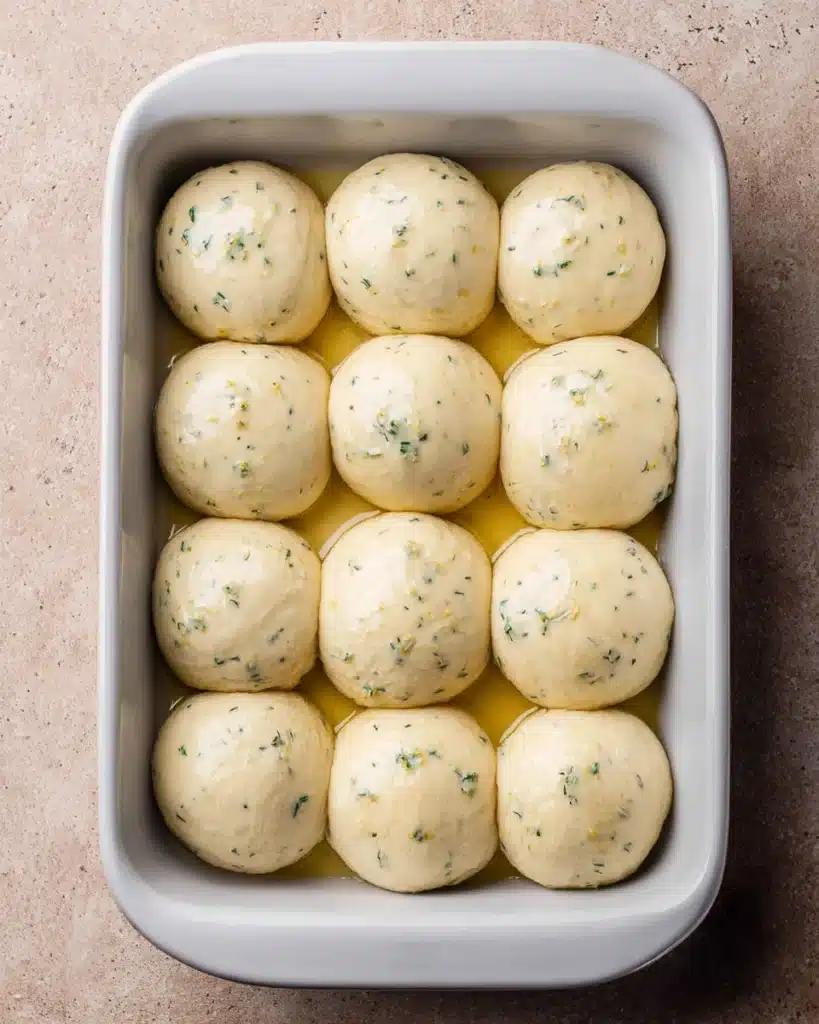 Easy Garlic Bread Rolls (Perfect for Thanksgiving) 5 Risen dough balls in baking dish for Easy Garlic Bread Rolls