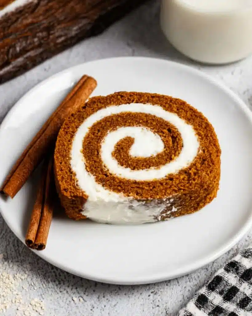 Fall Pumpkin Spice Roll Cake (Perfect Thanksgiving Dessert) 8 Slice of Fall Pumpkin Spice Roll Cake with cream cheese swirl on white plate