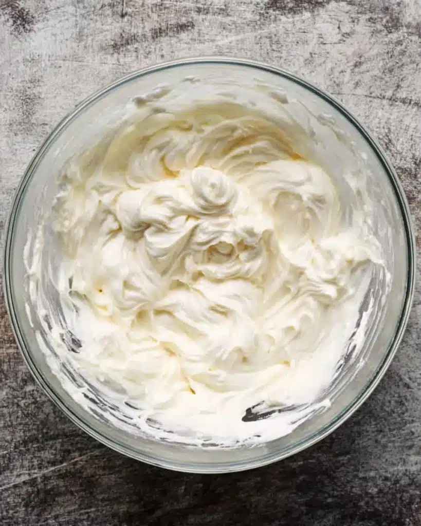 Fall Pumpkin Spice Roll Cake (Perfect Thanksgiving Dessert) 6 Cream cheese frosting in a glass bowl for Fall Pumpkin Spice Roll Cake filling