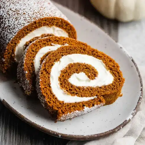Fall Pumpkin Spice Roll Cake (Perfect Thanksgiving Dessert) 10 Pumpkin spice roll cake with cream cheese filling sliced on a white platter