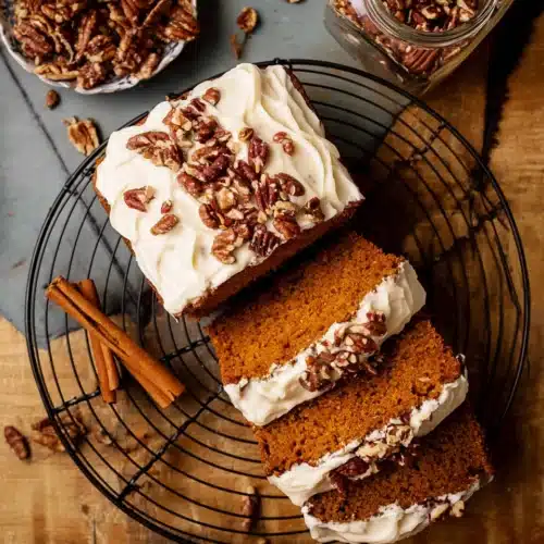 Frosted Pumpkin Bread 13 Sliced frosted pumpkin bread with cream cheese frosting and pecans on a rustic table