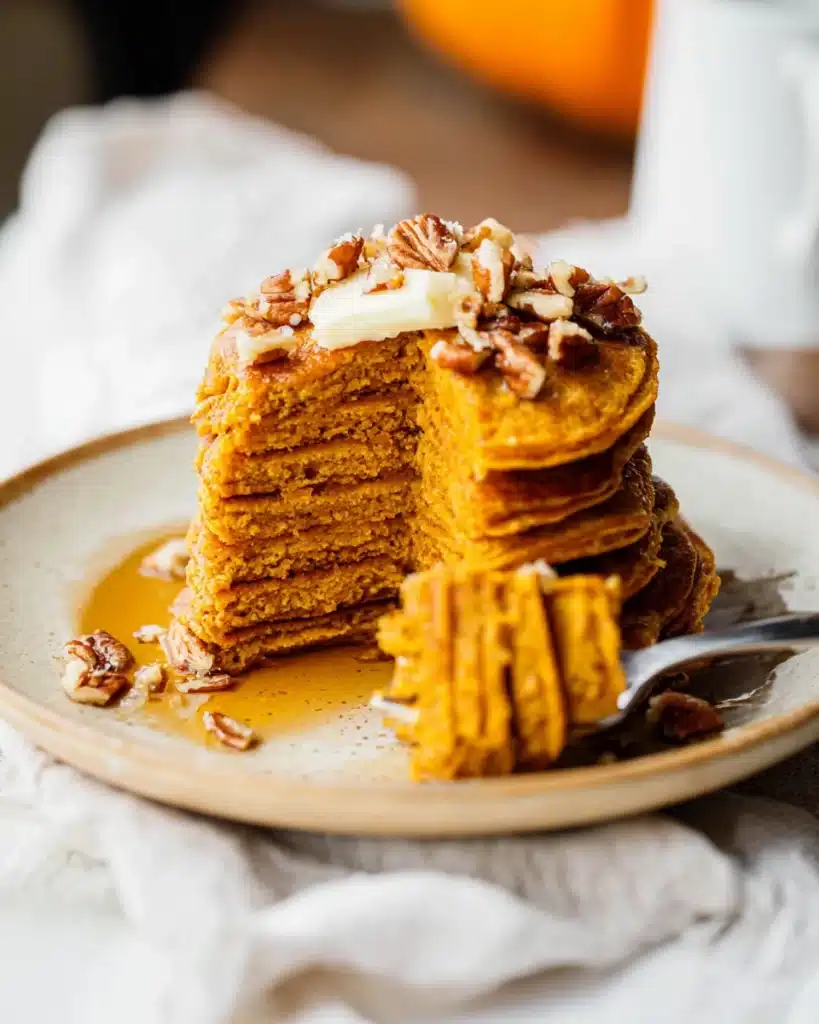 Fluffy healthy pumpkin pancakes cut open with butter and pecans