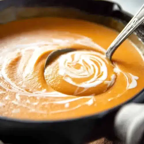 Pumpkin Soup 6 Creamy pumpkin soup in a black bowl with cream swirl and ladle