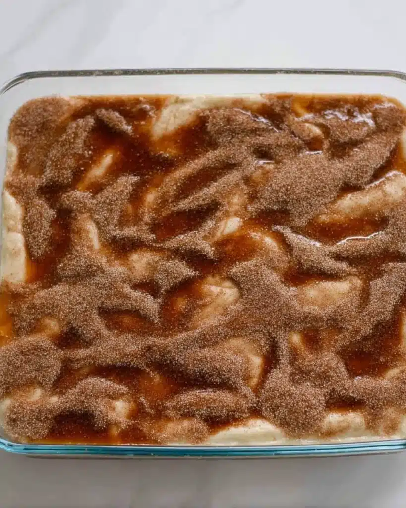 Glass dish of Simple Churro Cheesecake topped with cinnamon sugar before baking