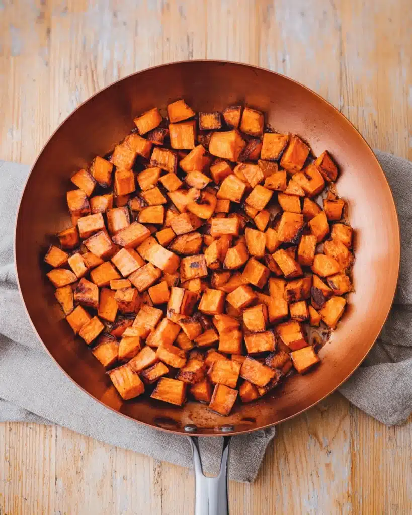 Sweet Potato Breakfast Hash (Thanksgiving Recipe) 3 Crispy caramelized sweet potatoes cooking in skillet for breakfast hash