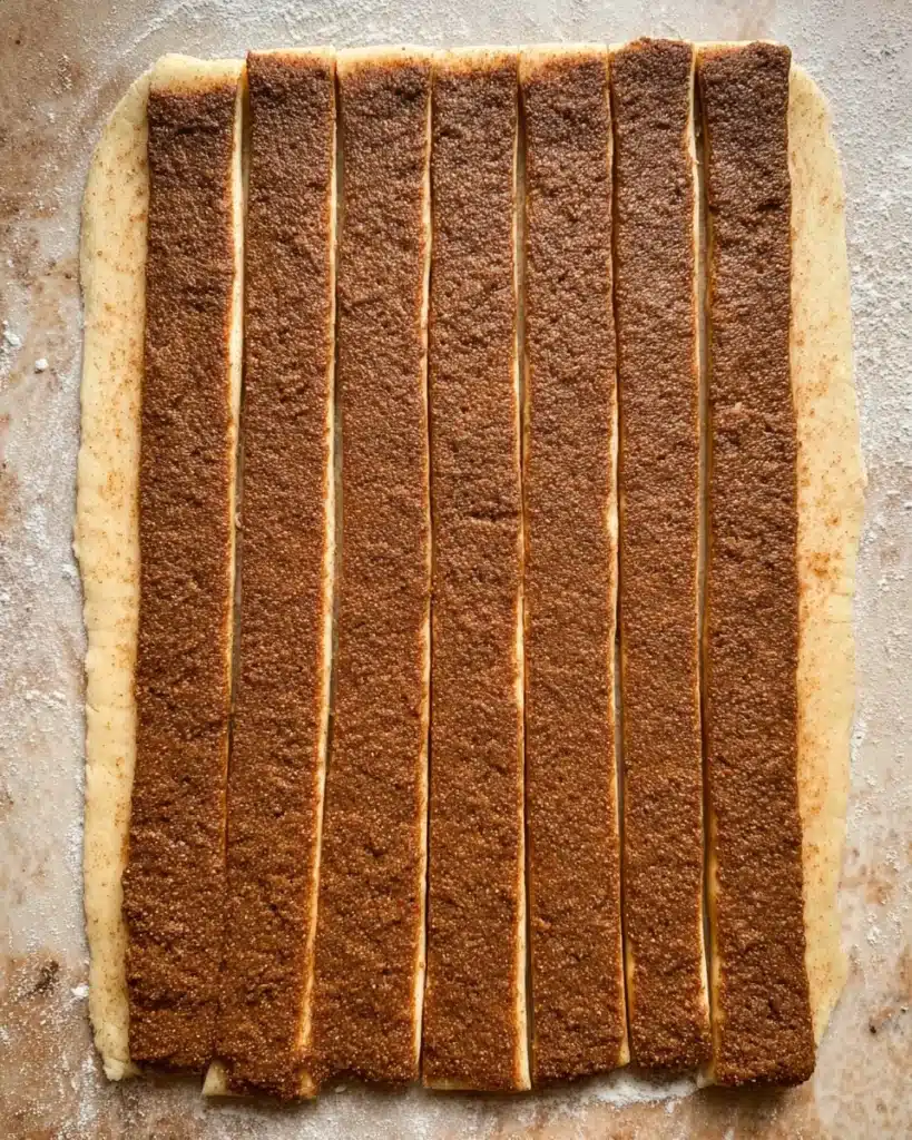 The Best Cinnamon Rolls EVER (Halloween Edition) 8 Cinnamon roll dough cut into strips with filling spread evenly