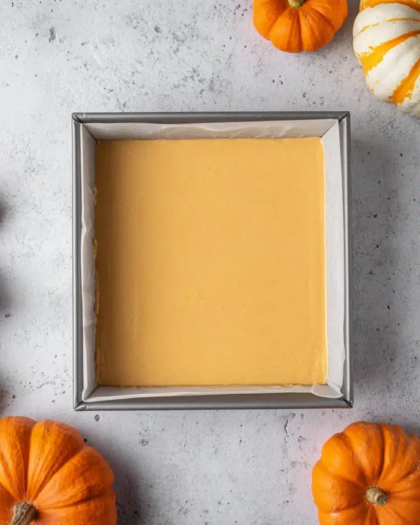 The Best Pumpkin Cheesecake Bars Ever 7 Pumpkin cheesecake batter in baking pan with pumpkins