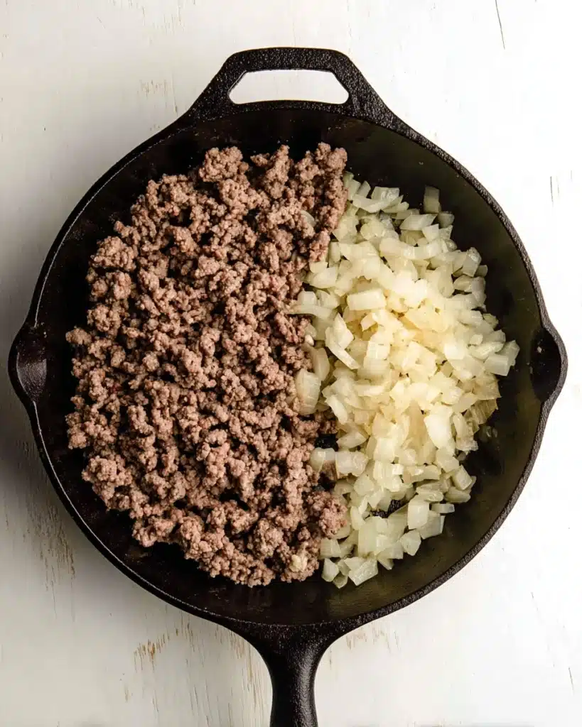 Whole30 Sloppy Joes 3 Ground beef and onions cooking in cast iron skillet for Whole30 sloppy joes
