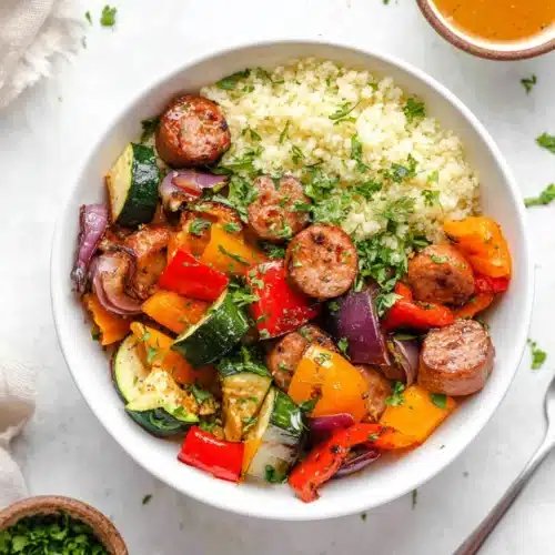 Air fryer chicken sausage and veggies with cauliflower rice in a white bowl