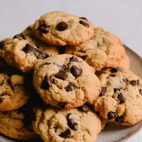 Golden-brown air fryer chocolate chip cookies stacked on a white plate