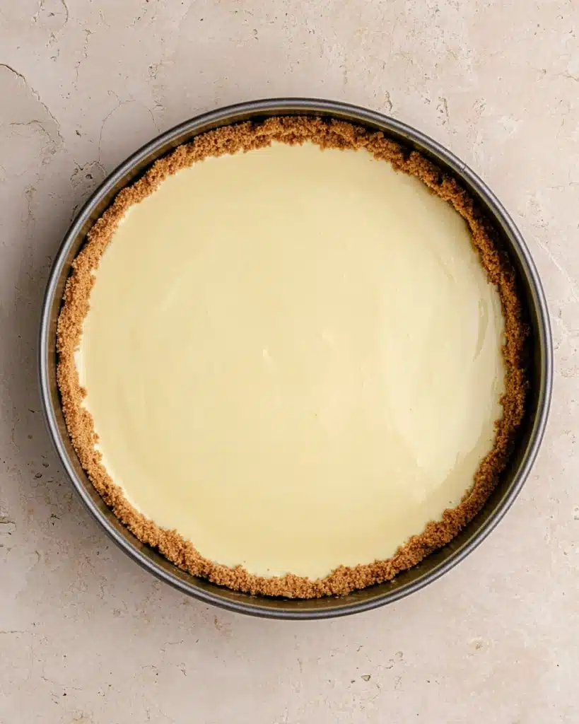 Springform pan with creamy cheesecake batter poured over crust
