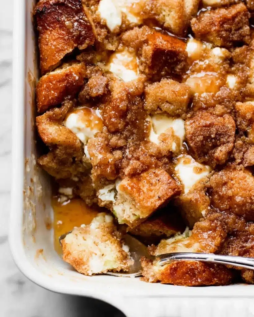 Close-up of baked cream cheese French toast casserole in white dish with crumb topping