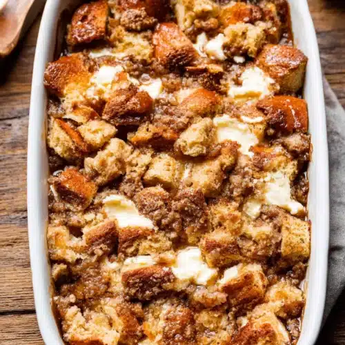 Golden baked cream cheese French toast casserole with crumb topping in white dish