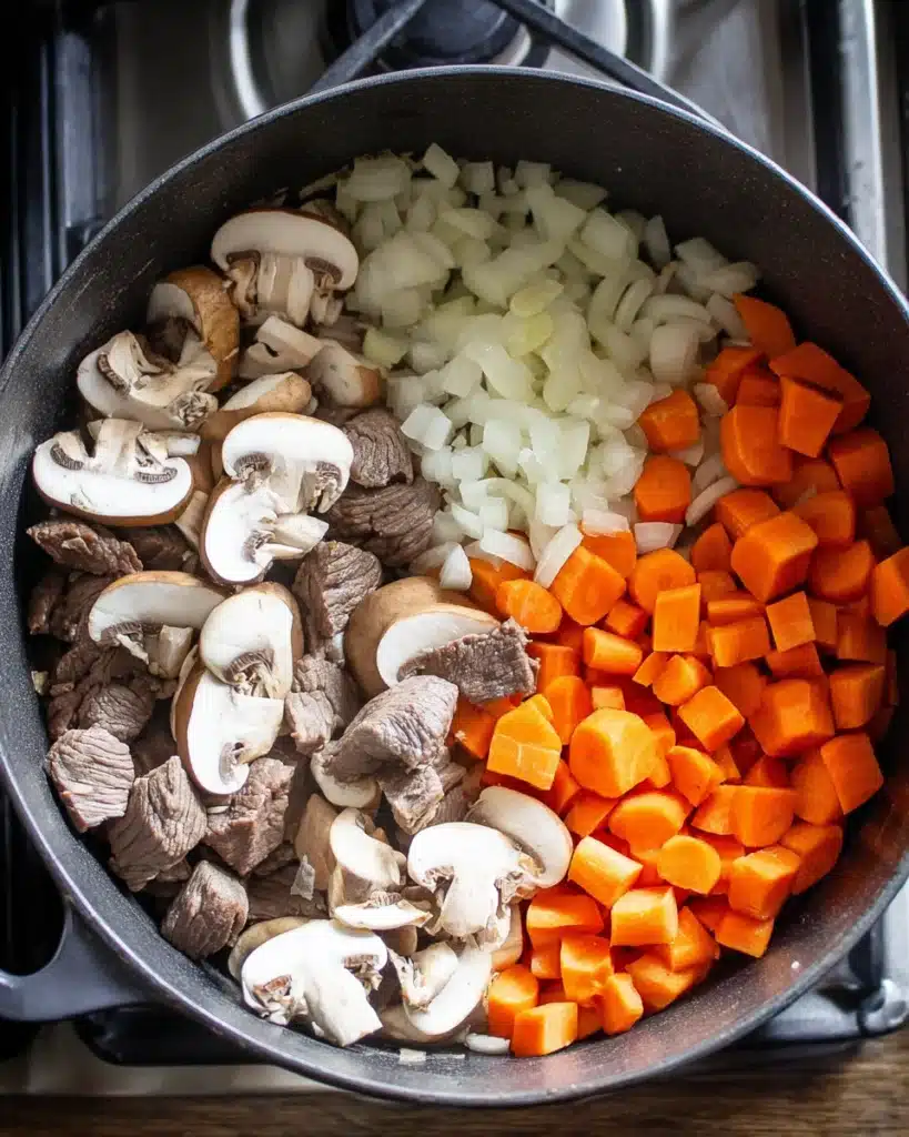 Beef Barley Soup Recipe (Hearty, Comforting & Easy to Make) 2 Beef barley soup ingredients with onions, carrots, mushrooms, and beef in pot