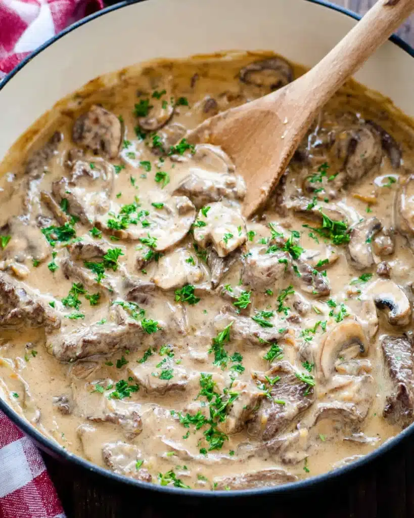Beef Stroganoff Recipe 1 Creamy beef stroganoff with mushrooms in a skillet topped with fresh herbs