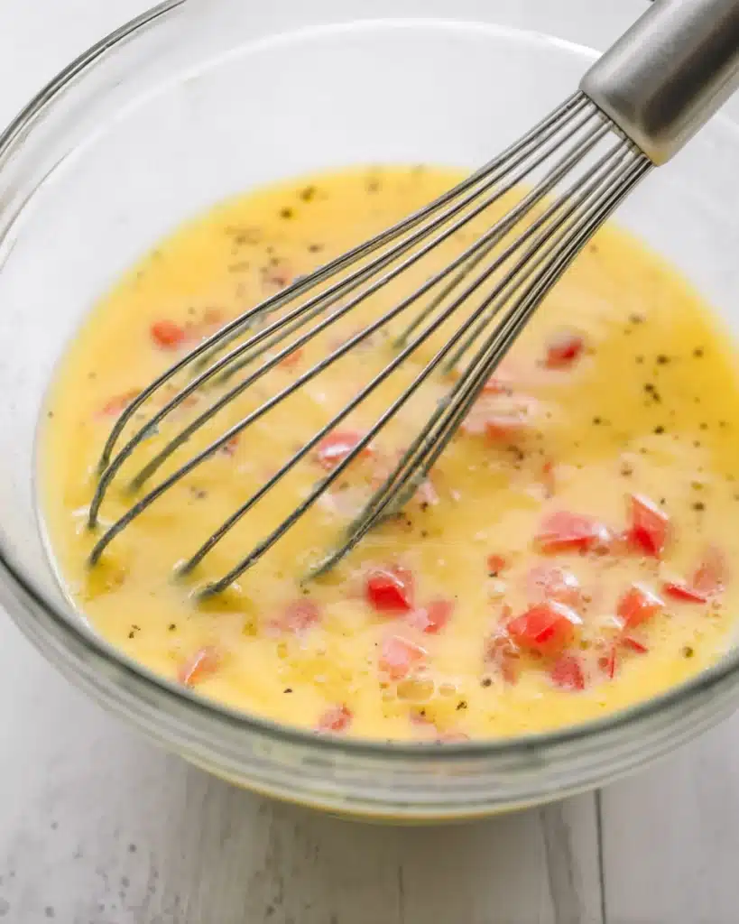 Breakfast Rolls 2 Whisked eggs with red bell peppers in a glass bowl