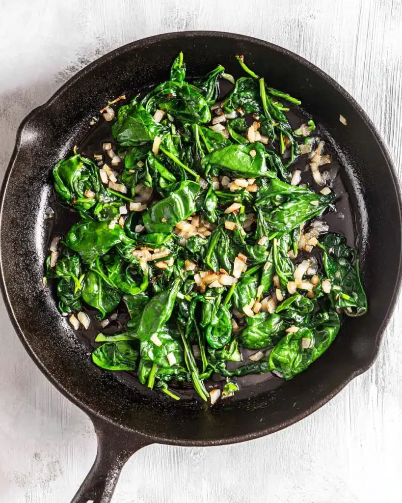 Breakfast Sandwiches: Easy, Freezer-Friendly Morning Meal 3 sautéed spinach and onions in cast iron skillet for breakfast sandwiches