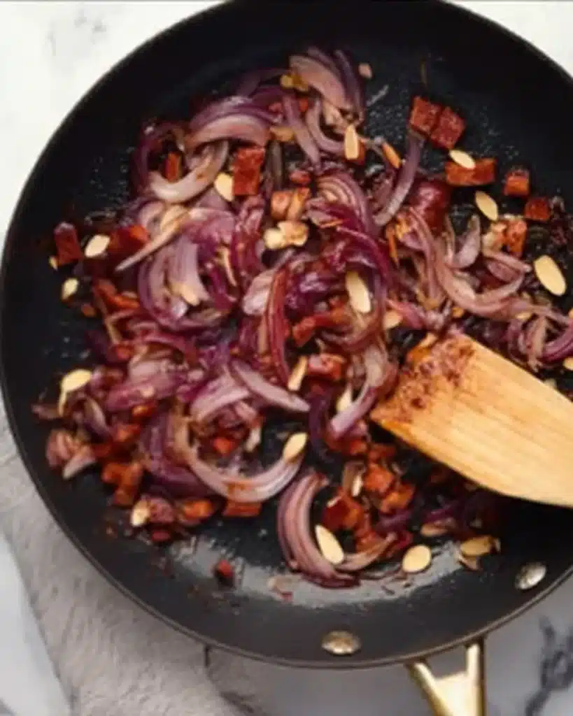 Broccoli Pearl Crunch Salad 5 Sautéing red onion, salami, and almonds in a skillet for Broccoli Pearl Crunch Salad