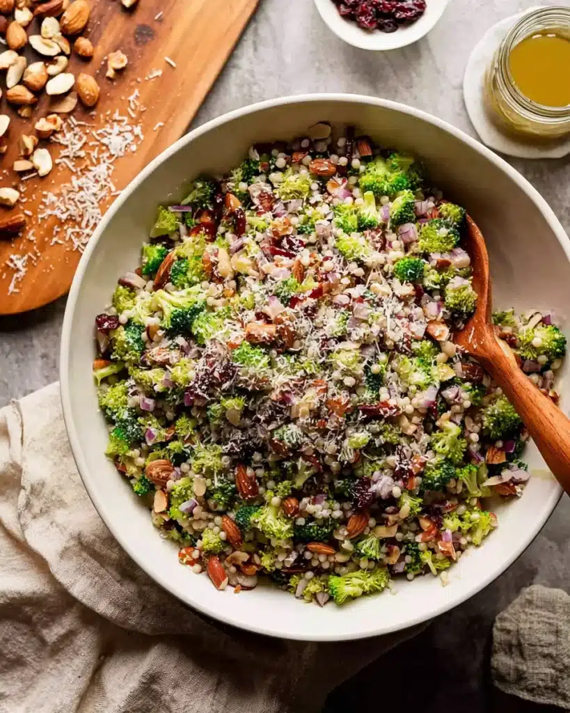Broccoli Pearl Crunch Salad 7 Broccoli Pearl Crunch Salad being mixed in a white bowl with wooden spoon