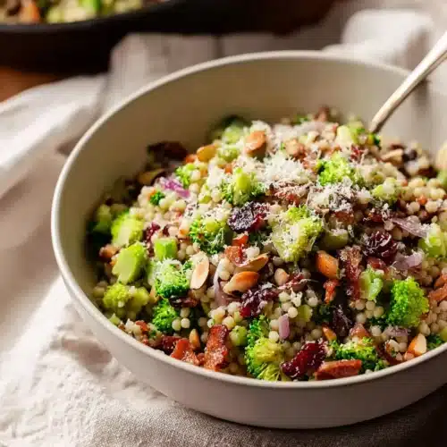 Broccoli Pearl Crunch Salad 8 Broccoli pearl couscous salad with almonds, cranberries, and cheese in a white bowl