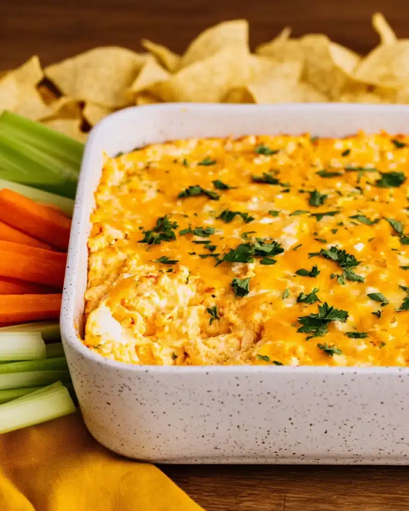Buffalo Chicken Dip Recipe (Easy, Creamy & Crowd-Pleasing) 3 Buffalo chicken dip with melted cheddar and parsley in white baking dish