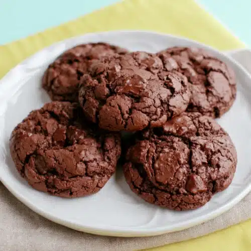 Cake Mix Cookies – The Easiest 3-Ingredient Dessert Ever! 6 Chocolate cake mix cookies on a white plate with chocolate chips and a bright background