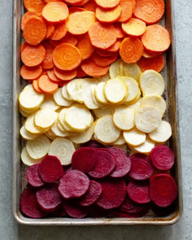 Cheesy Root Vegetable Gratin 2 Sliced colorful root vegetables for cheesy root vegetable gratin on a baking sheet