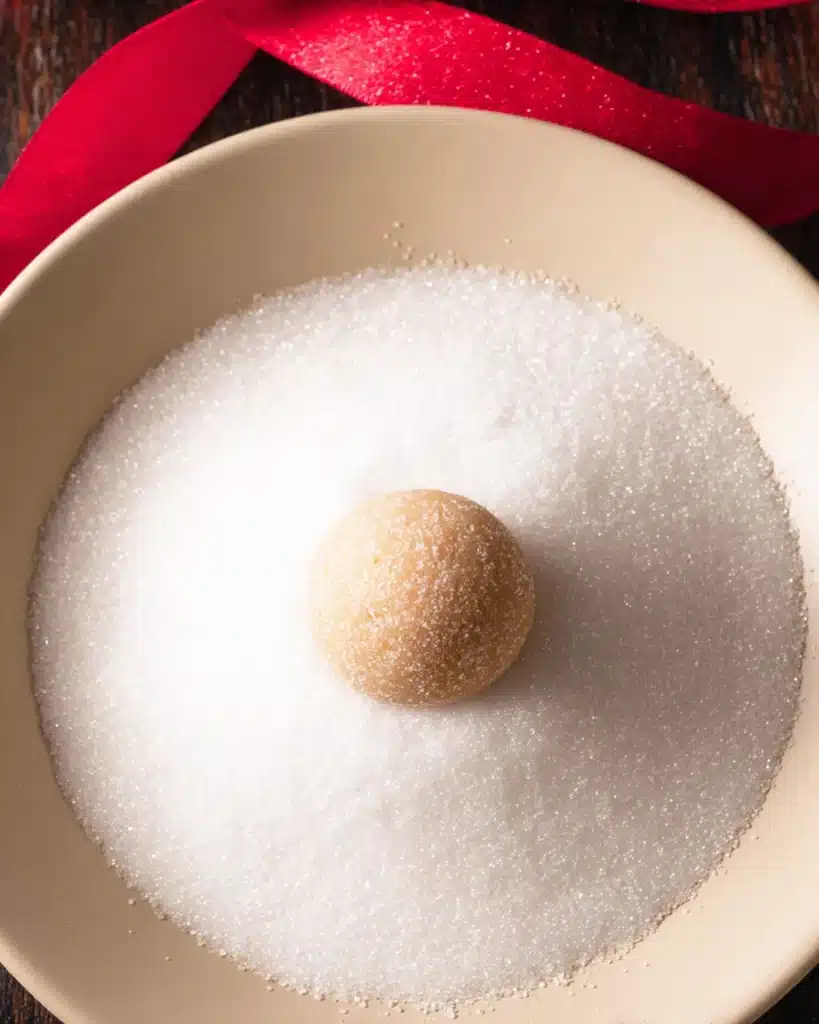 Chewy Sugar Cookies 5 Cookie dough ball in a bowl of sugar ready for rolling