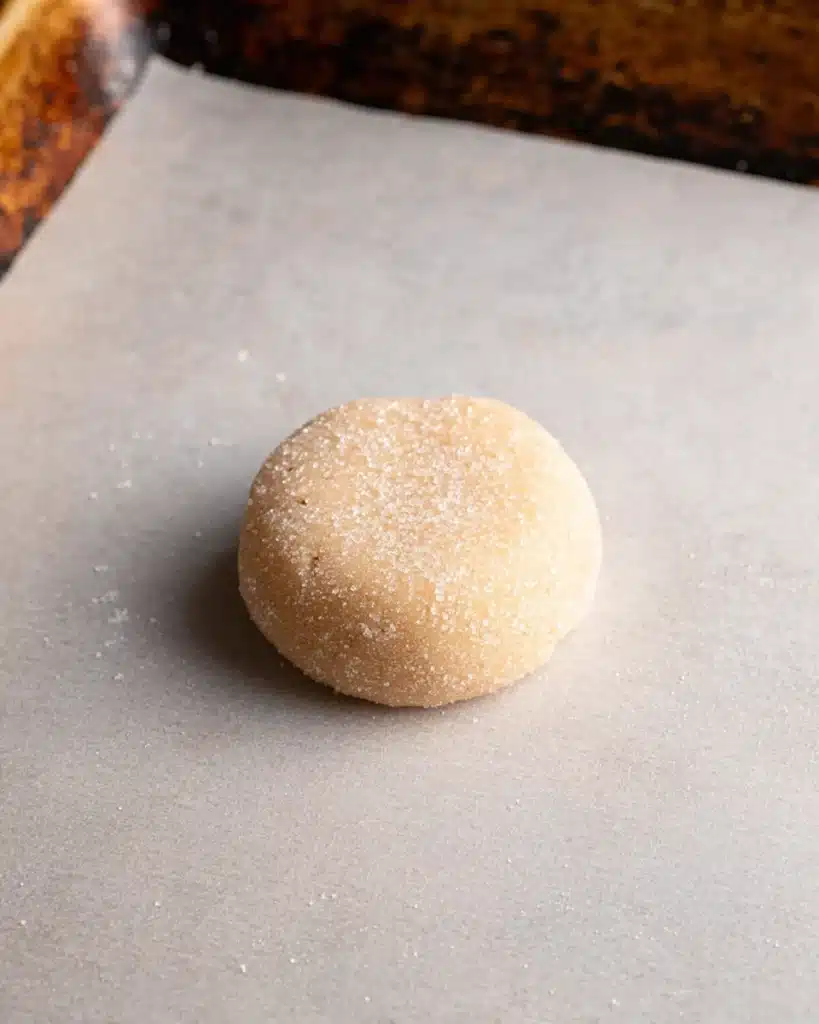 Chewy Sugar Cookies 6 Sugar-coated cookie dough ball on a parchment-lined baking sheet