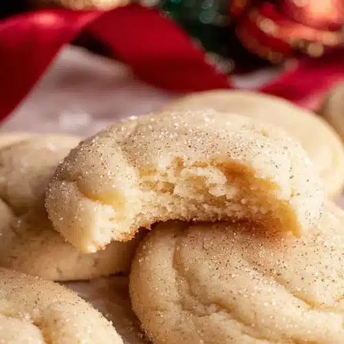 Chewy Sugar Cookies 9 Chewy sugar cookies with sugar dusting and a bite taken out on parchment paper