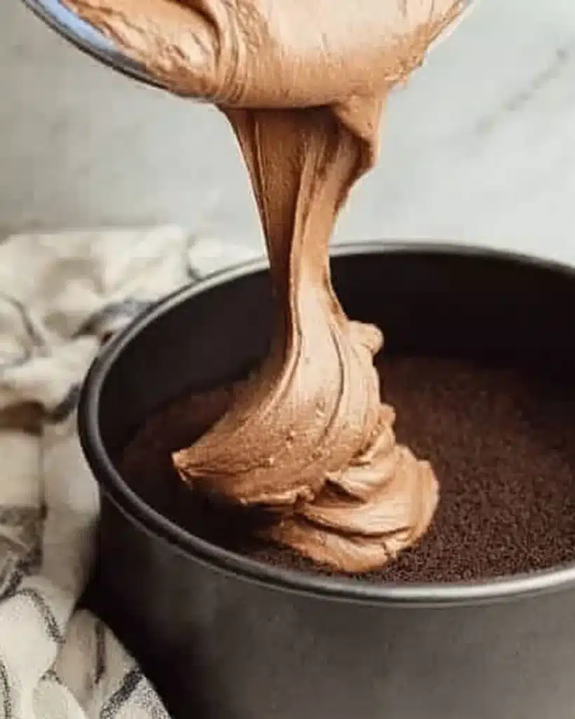Chocolate Cheesecake 3 Pouring creamy chocolate cheesecake batter into cookie crust