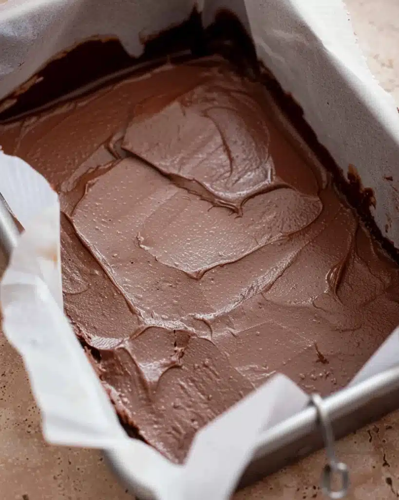 Christmas Fudge Recipe 3 Chocolate fudge layer spread in a parchment-lined pan