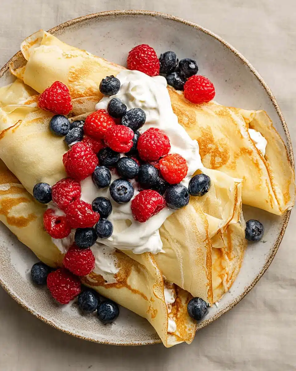 Crepes with Pancake Mix and Fresh Berries Folded crepes with whipped cream, raspberries, and blueberries on a plate