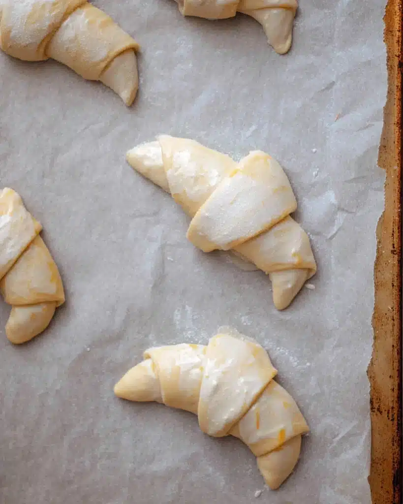 Ground Beef Crescent Rolls 2 Unbaked ground beef crescent rolls on parchment-lined baking sheet