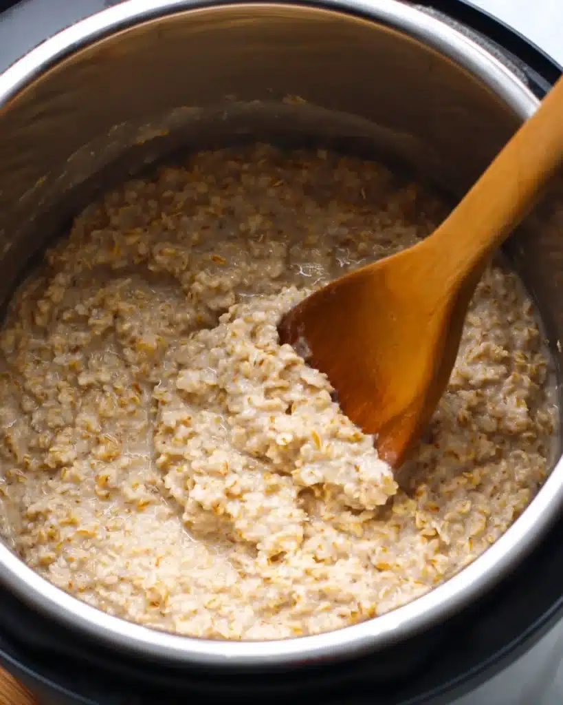 Instant Pot Steel Cut Oats 4 Creamy steel cut oats stirred with a wooden spoon in an Instant Pot