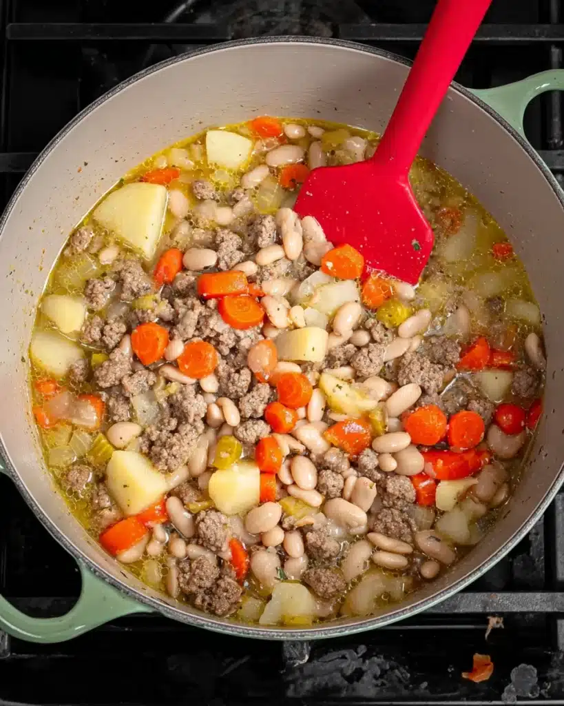 Italian Sausage and White Bean Soup (with Tuscan Kale) 6 Italian sausage, beans, carrots, and potatoes simmering in a pot for white bean soup