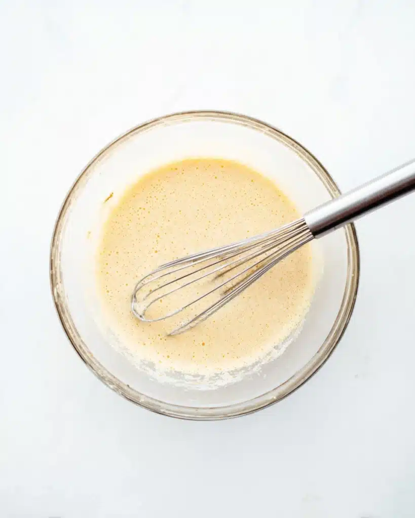 Whisking wet ingredients for Oatmeal Apple Breakfast Bake in a glass bowl