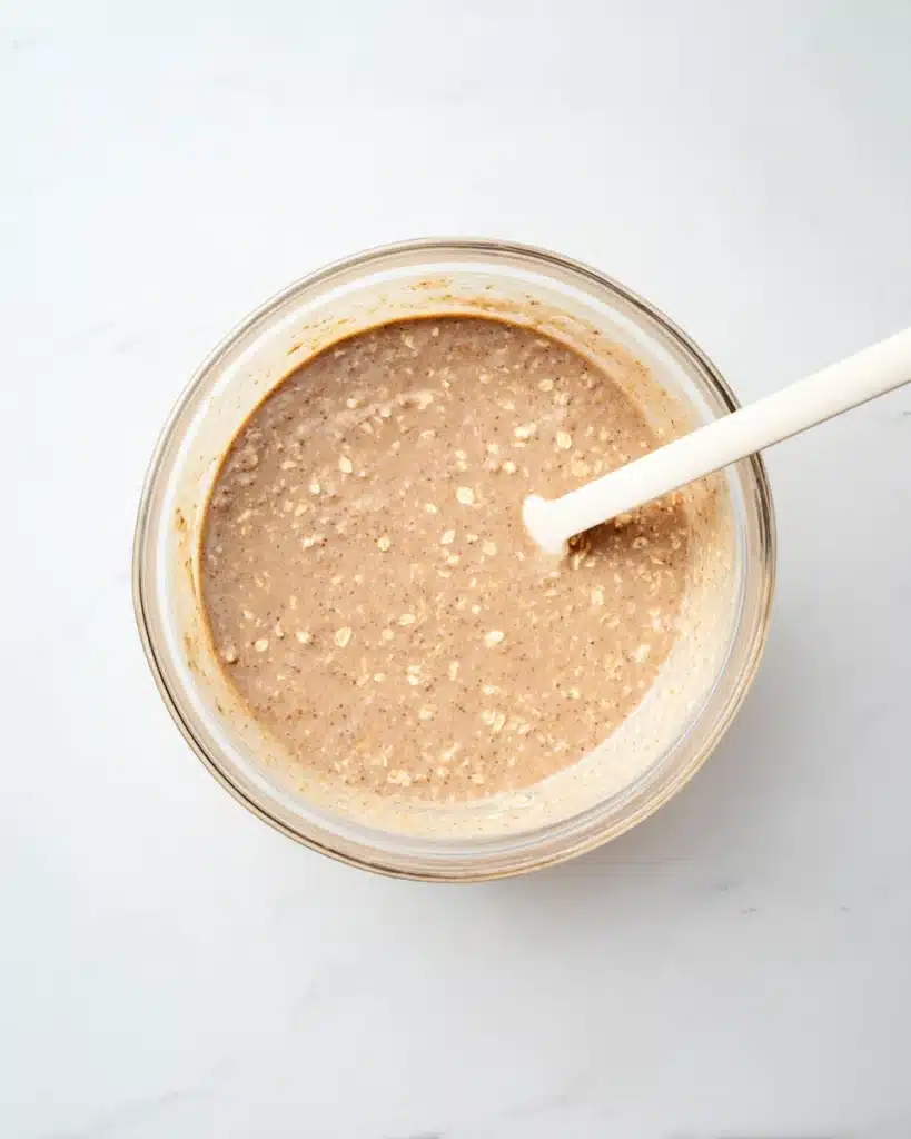 Oatmeal Apple Breakfast Bake batter in a glass bowl with white spatula