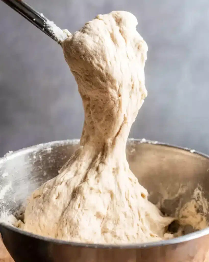 Quick and Dirty Focaccia 3 Sticky focaccia dough being lifted from metal bowl
