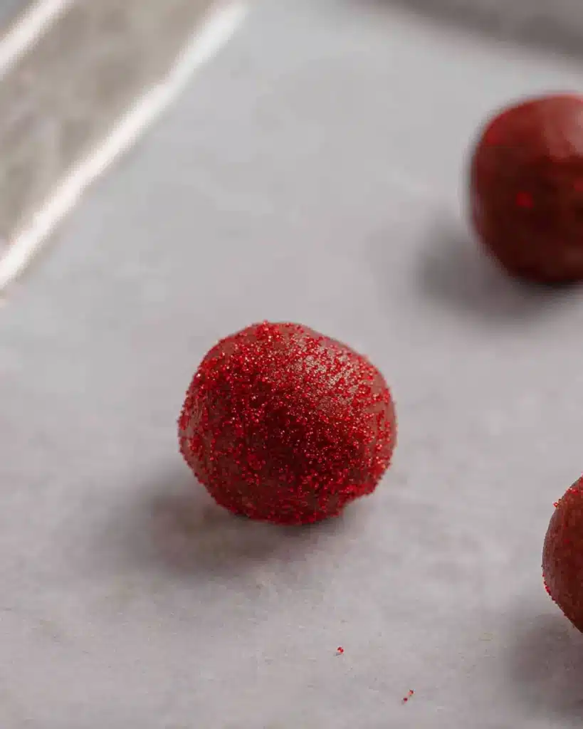 Red Velvet Blossoms Cookies – Soft, Sweet, and Perfectly Festive 6 Red velvet cookie dough balls on a baking sheet before baking