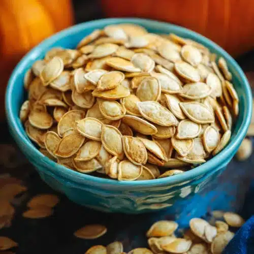 Roasted Pumpkin Seeds Recipe 8 Golden roasted pumpkin seeds in a blue bowl on autumn table